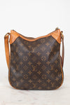 A Louis Vuitton monogram canvas shoulder bag with tan leather trim and a gold-tone zipper, displayed on a light marble surface against a white background.