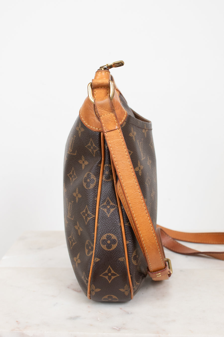 A Louis Vuitton monogram coated canvas shoulder bag shown from the side, featuring brown coated canvas with tan monogram motifs and light brown leather trim and strap, set against a plain white background.