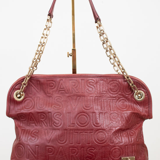 A Louis Vuitton monogram embossed leather shoulder bag in burgundy red, featuring gold-tone chain handles and a tassel detail, displayed on a white background.