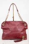 A Louis Vuitton monogram embossed leather shoulder bag in burgundy red, featuring gold-tone chain handles and a tassel detail, displayed on a white background.