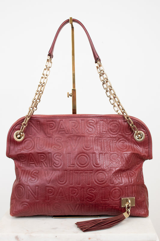 A Louis Vuitton monogram embossed leather shoulder bag in burgundy red, featuring gold-tone chain handles and a tassel detail, displayed on a white background.
