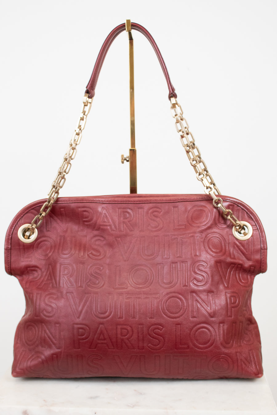 A Louis Vuitton shoulder bag in burgundy embossed leather with a gold-tone chain strap and a top handle, displayed on a white background.