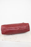 A Louis Vuitton burgundy leather shoulder bag with an embossed monogram pattern, resting on a white marble surface against a white background.