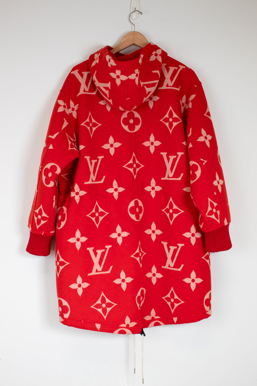 Red hoodie with pink patterns on a hanger against a white background