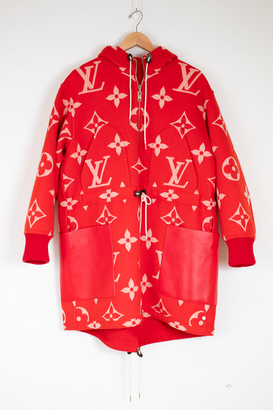 Red hoodie with pink patterns on a hanger against a white background