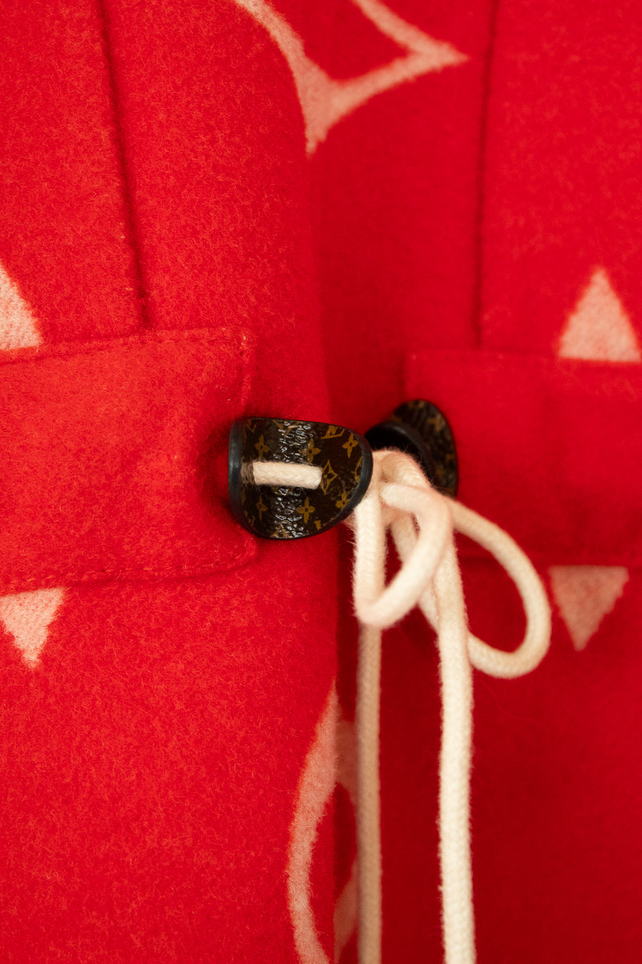 Close-up of a red fabric with a button and white drawstring on a red background