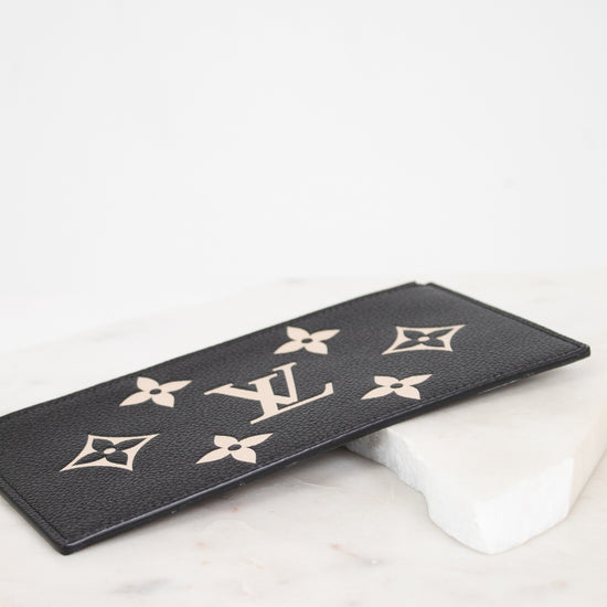 A black leather Louis Vuitton monogram patch with gold-tone LV logos and floral motifs, resting on a white marble block against a white background.