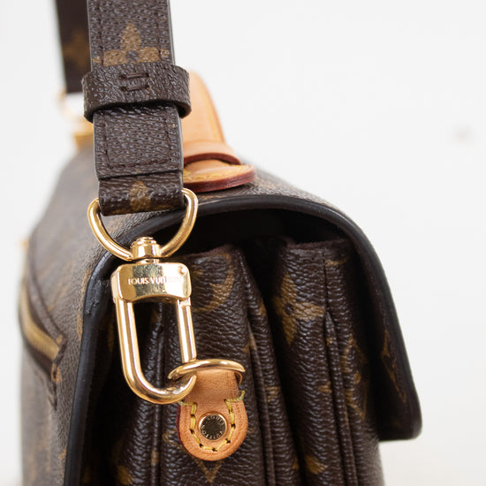 Close-up of a Louis Vuitton shoulder bag in brown monogram canvas with gold-tone hardware and a dark brown leather strap, shown against a plain light background.