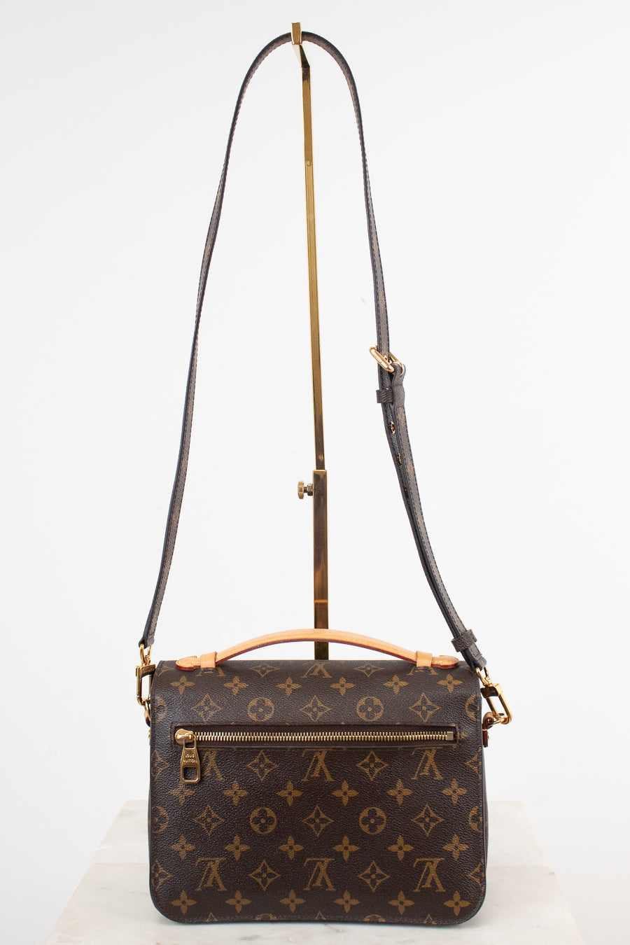 Louis Vuitton monogram shoulder bag in dark brown coated canvas with gold-tone hardware, displayed on a white background with a stand.
