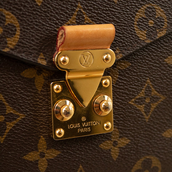 Close-up of a Louis Vuitton monogram handbag in brown coated canvas with gold-tone hardware and a tan leather strap tab, showing the Louis Vuitton Paris engraved clasp.