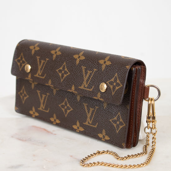 A Louis Vuitton monogram canvas clutch bag with a gold-tone chain strap, resting on a white marble surface against a white background.