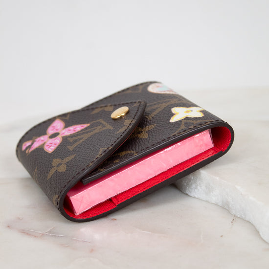 A Louis Vuitton monogram post-it note holder with multi-color accents, resting on a white marble surface against a light gray background.