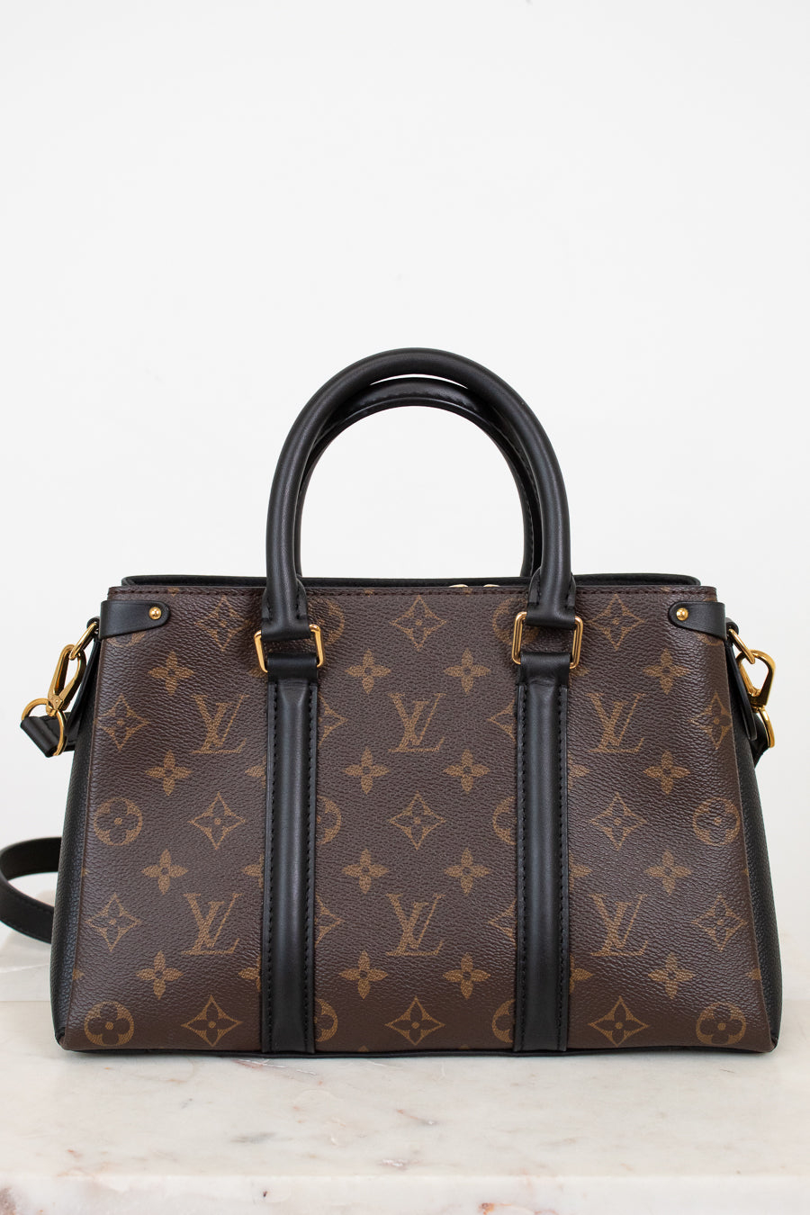 Brown handbag with tan monogram pattern on a white background