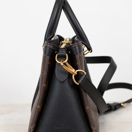 Black leather handbag with gold hardware on a light gray background