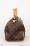 A Louis Vuitton monogram Speedy bag in brown coated canvas with tan leather trim and handles, shown from the side on a light gray background.
