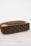 A Louis Vuitton monogram coated canvas handbag with tan leather trim viewed from the bottom, resting on a white marble surface against a white background.