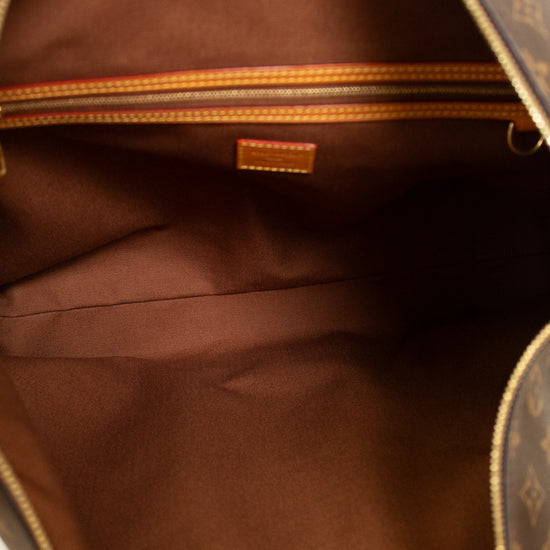 Close-up of the interior of a brown leather bag with gold details and tan logo.