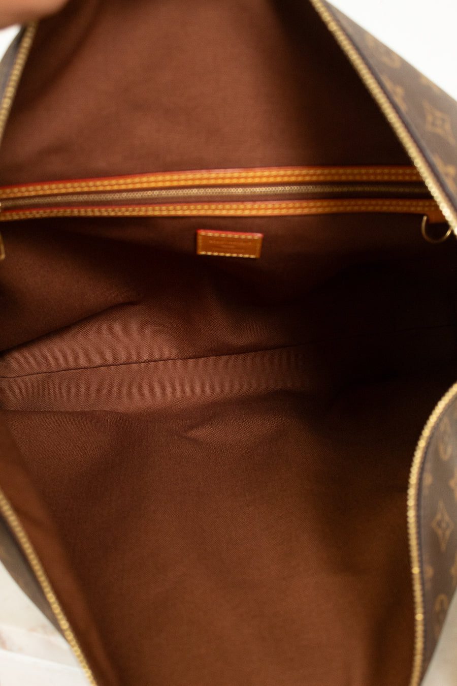 Close-up of the interior of a brown leather bag with gold details and tan logo.