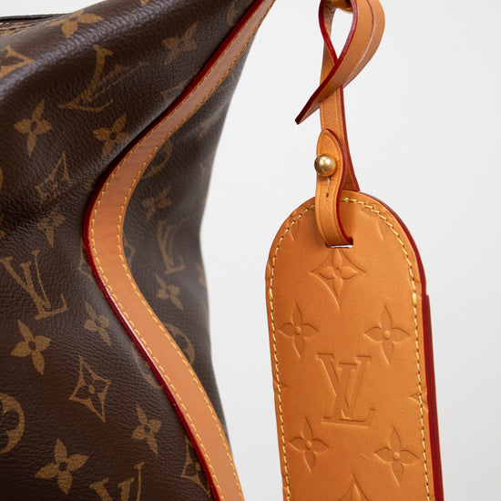 Brown handbag with monogram pattern and a matching tag on a white background