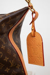 Brown handbag with monogram pattern and a matching tag on a white background
