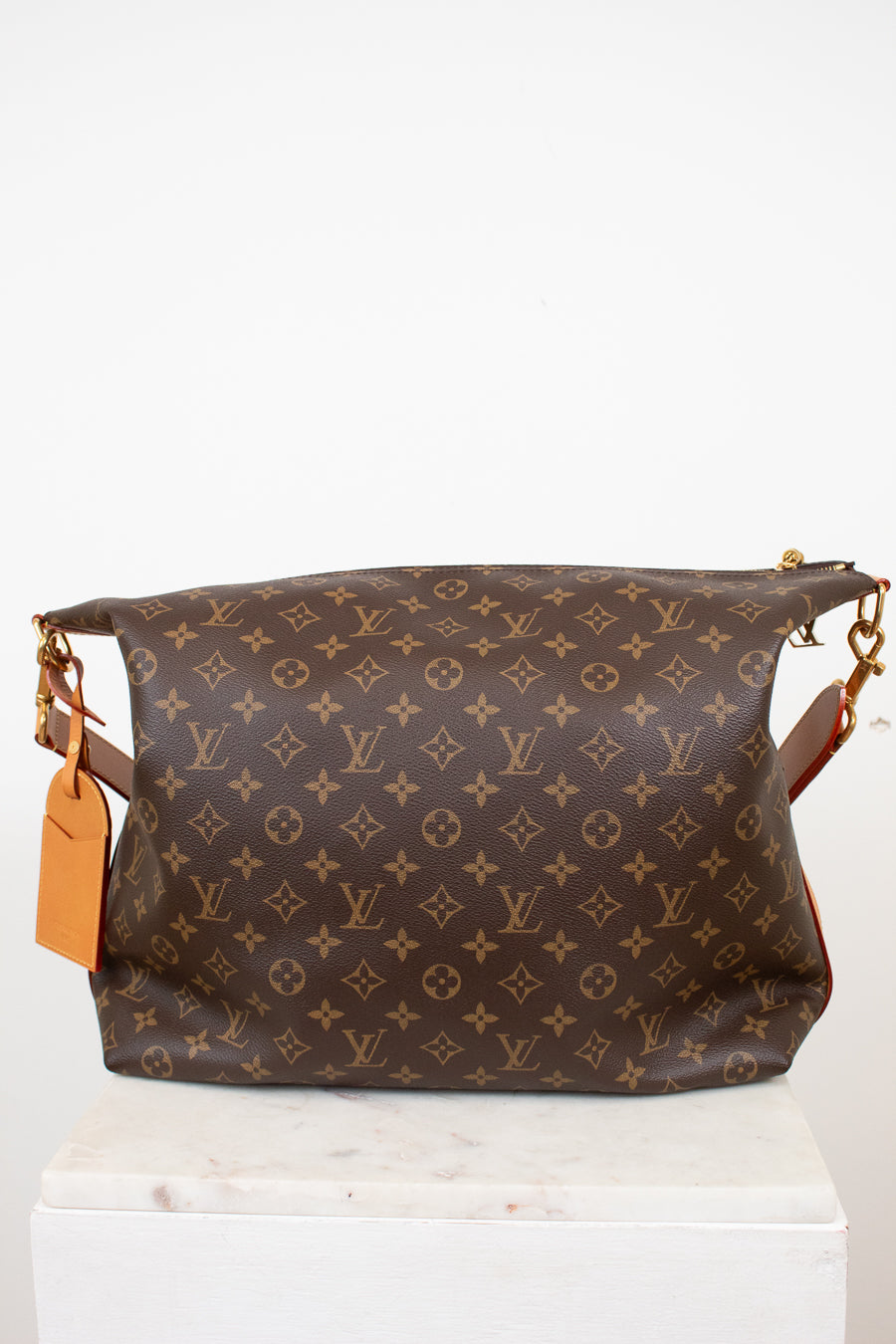 Brown monogram handbag with gold accents on a white background