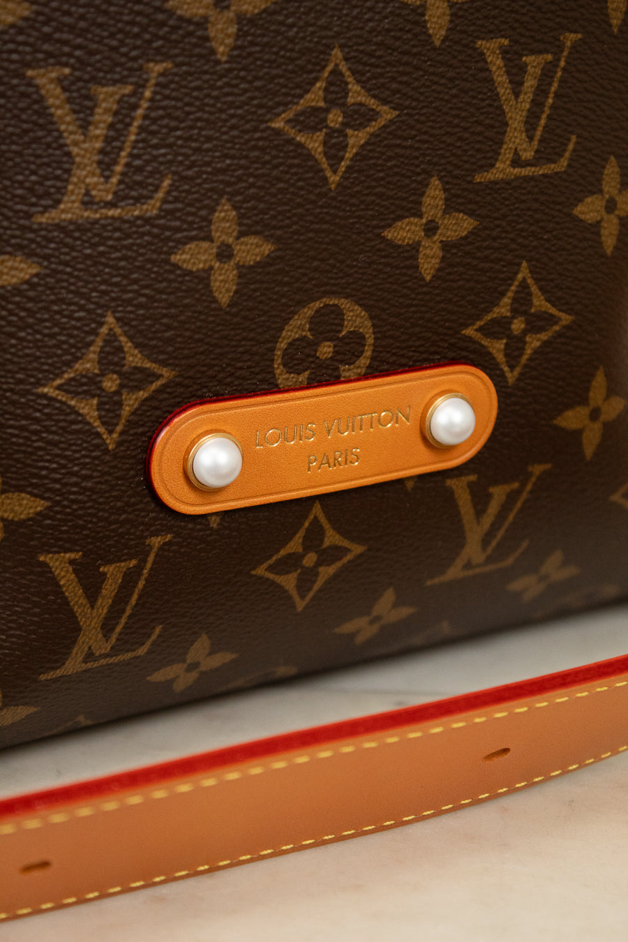 Close-up of a Louis Vuitton bag with monogram pattern and tan label.