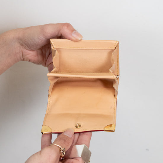 Hand holding an empty beige wallet against a plain background