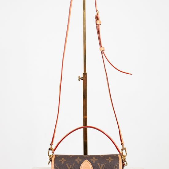 Designer handbag with monogram pattern and brown strap on a white background