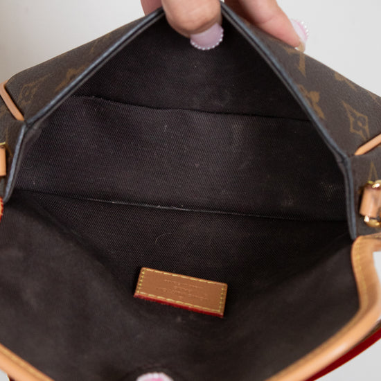 Close-up of a hand holding an open brown leather handbag with visible brand logo.
