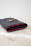 A dark navy blue leather wallet with a red interior lining and a gold-tone metal LV logo clasp, resting on a white marble slab against a white background.