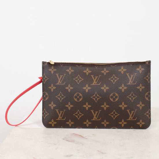 A Louis Vuitton monogram canvas wristlet pouch with a brown and tan pattern and a red wrist strap, resting on a white marble surface against a white background.