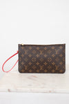 A Louis Vuitton monogram canvas wristlet pouch with a brown and tan pattern and a red wrist strap, resting on a white marble surface against a white background.