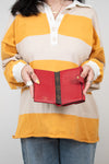 Person wearing a yellow and beige striped shirt holding a red wallet.