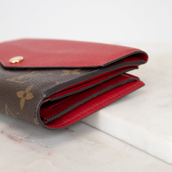 Louis Vuitton wallet with red interior on a marble surface