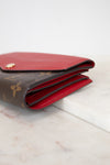 Louis Vuitton wallet with red interior on a marble surface
