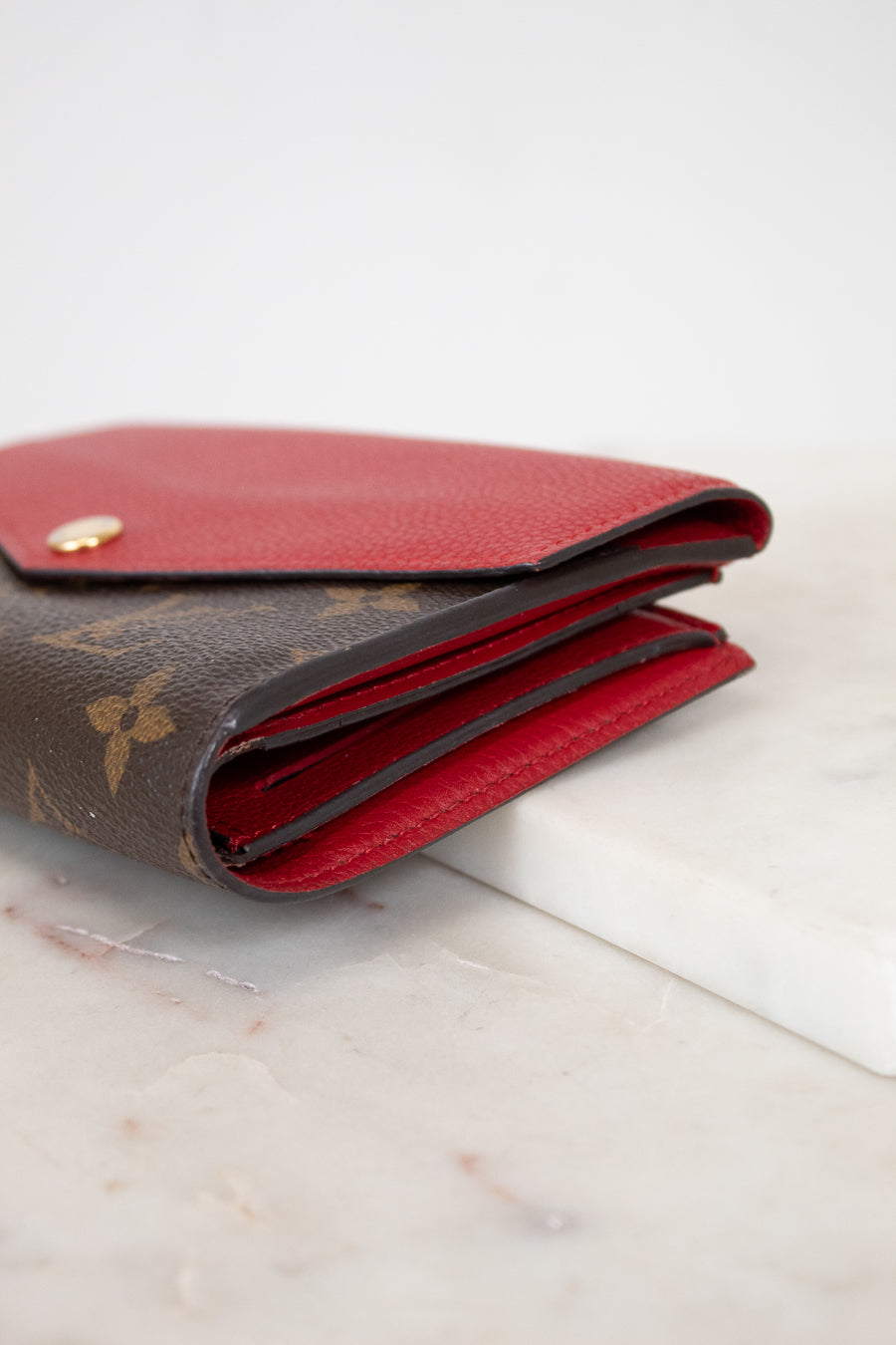 Louis Vuitton wallet with red interior on a marble surface