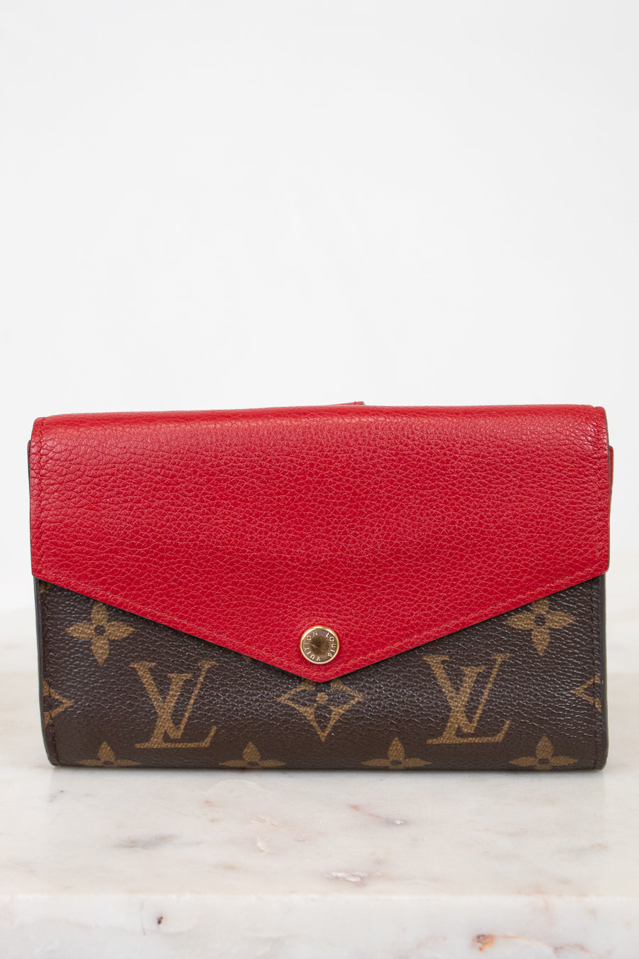 Red wallet with brown monogram pattern on a white background