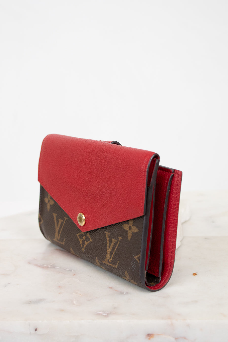 Red and brown wallet with Louis Vuitton monogram pattern on a white background