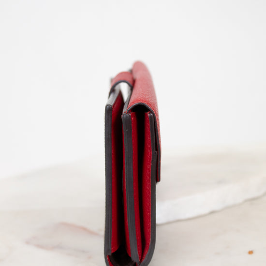 Red leather side view of wallet on a white marble surface