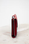 Red leather side view of wallet on a white marble surface
