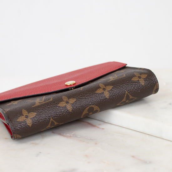 Brown wallet with red interior on a marble surface