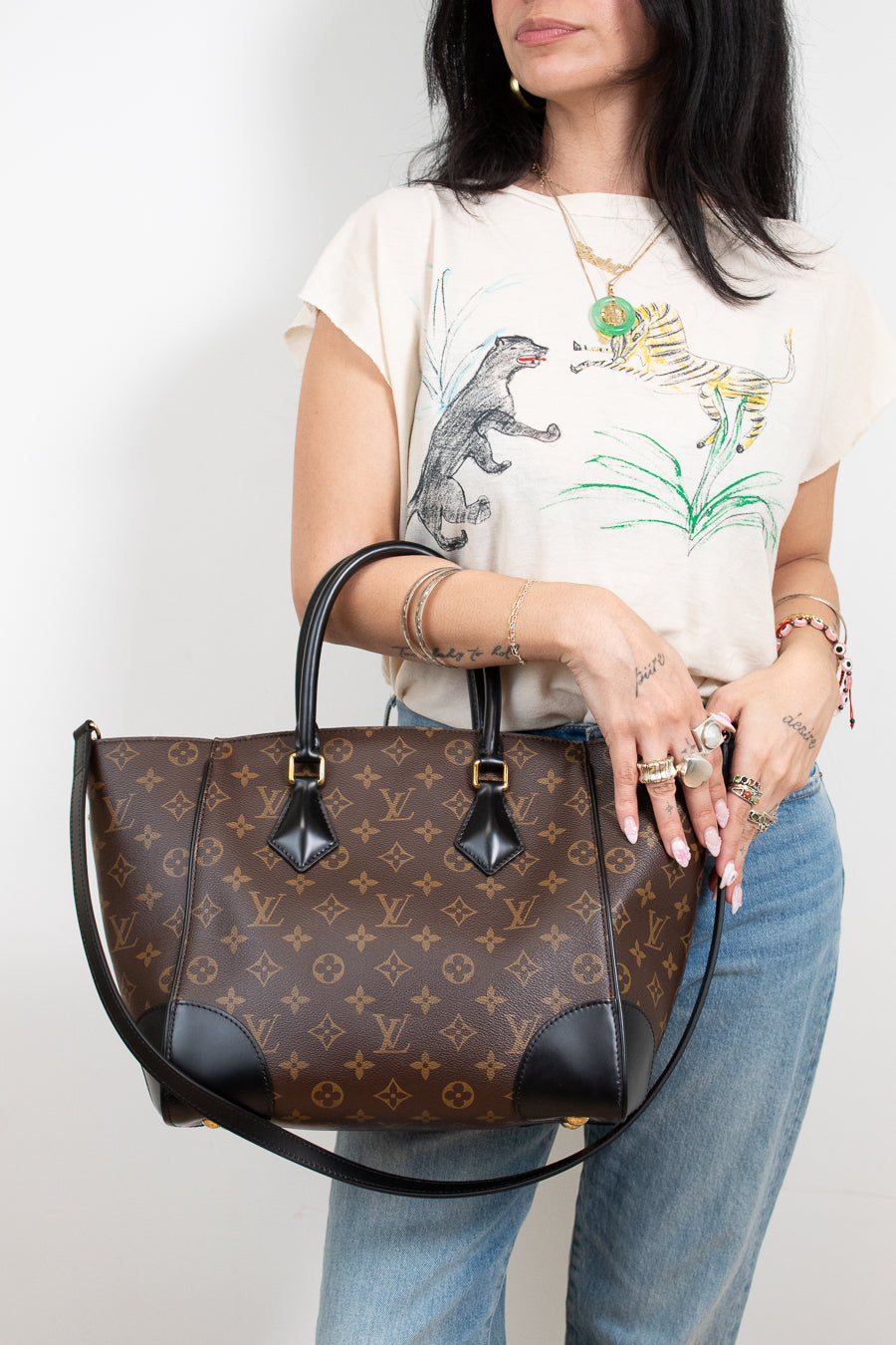 Person holding a brown patterned handbag with a plain background