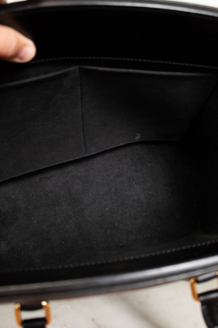 Close-up of a black leather briefcase with a hand holding it open.