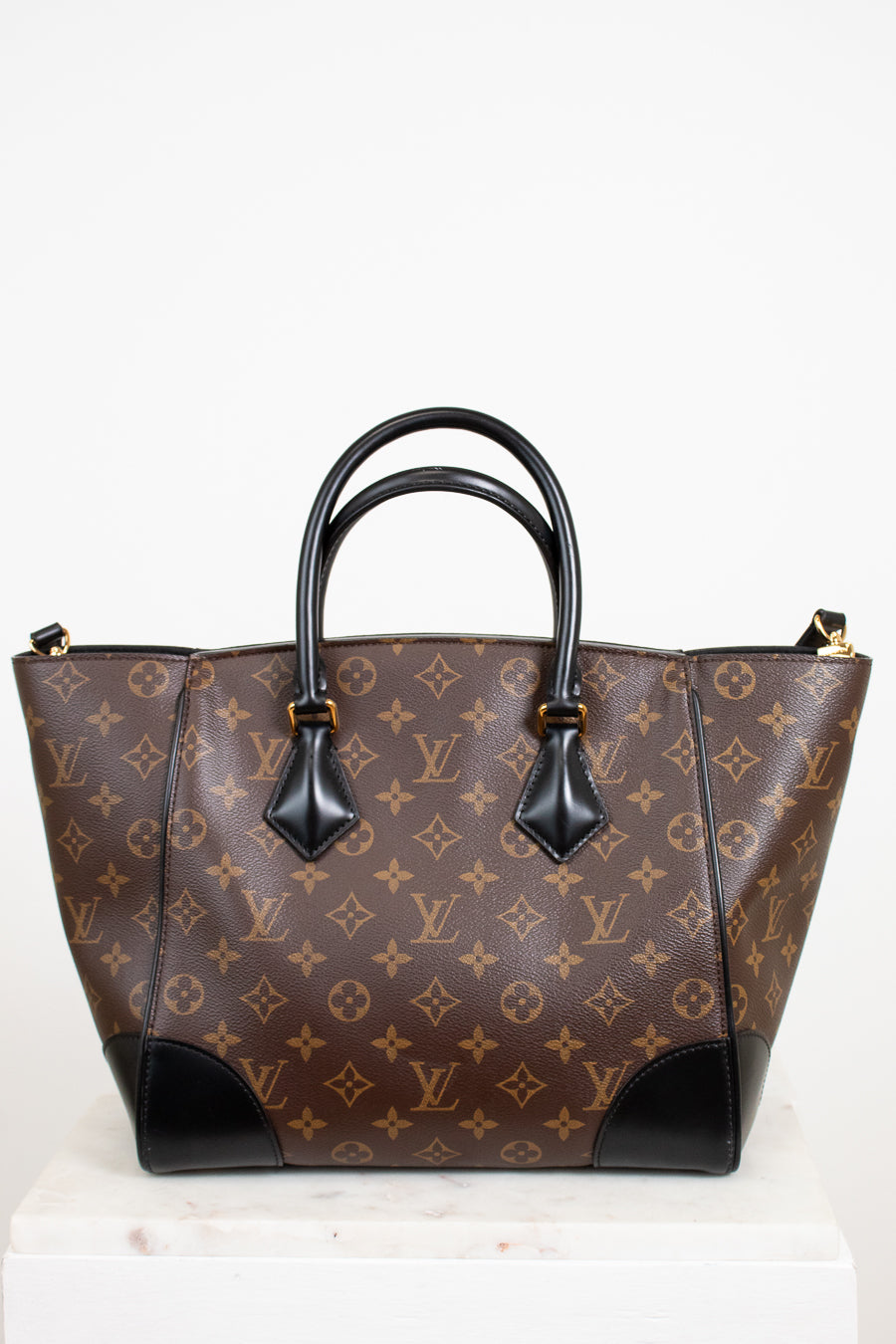 Brown handbag with black handles on a white background