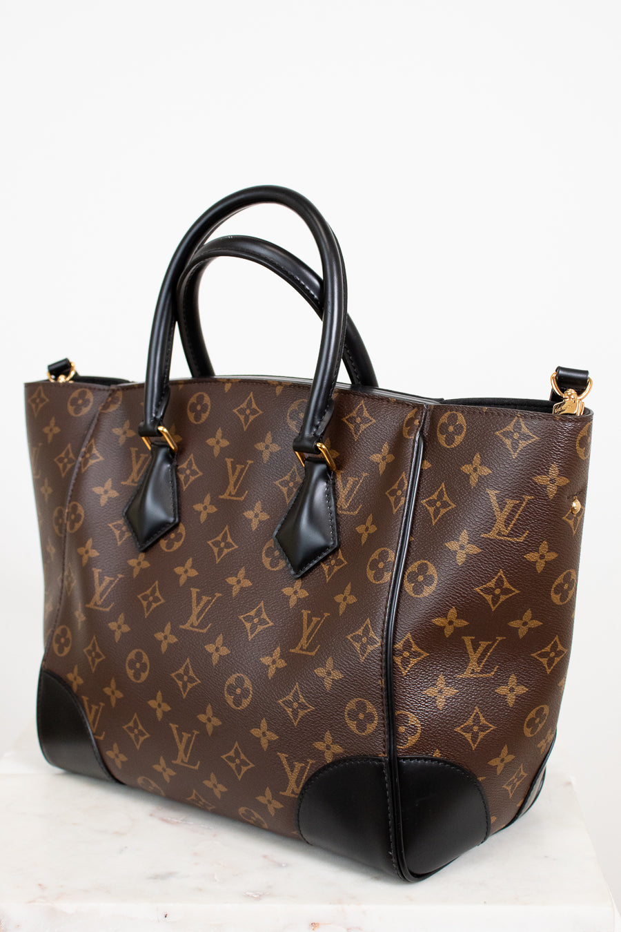 Brown handbag with black handles on a white background