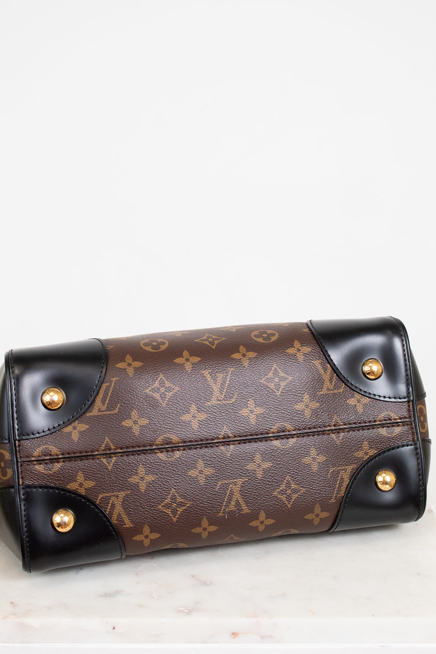 Designer handbag with monogram pattern and gold hardware on a light background