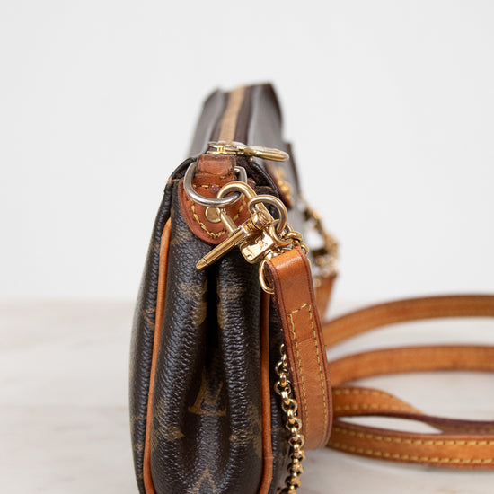Brown leather handbag with gold accents on a light background