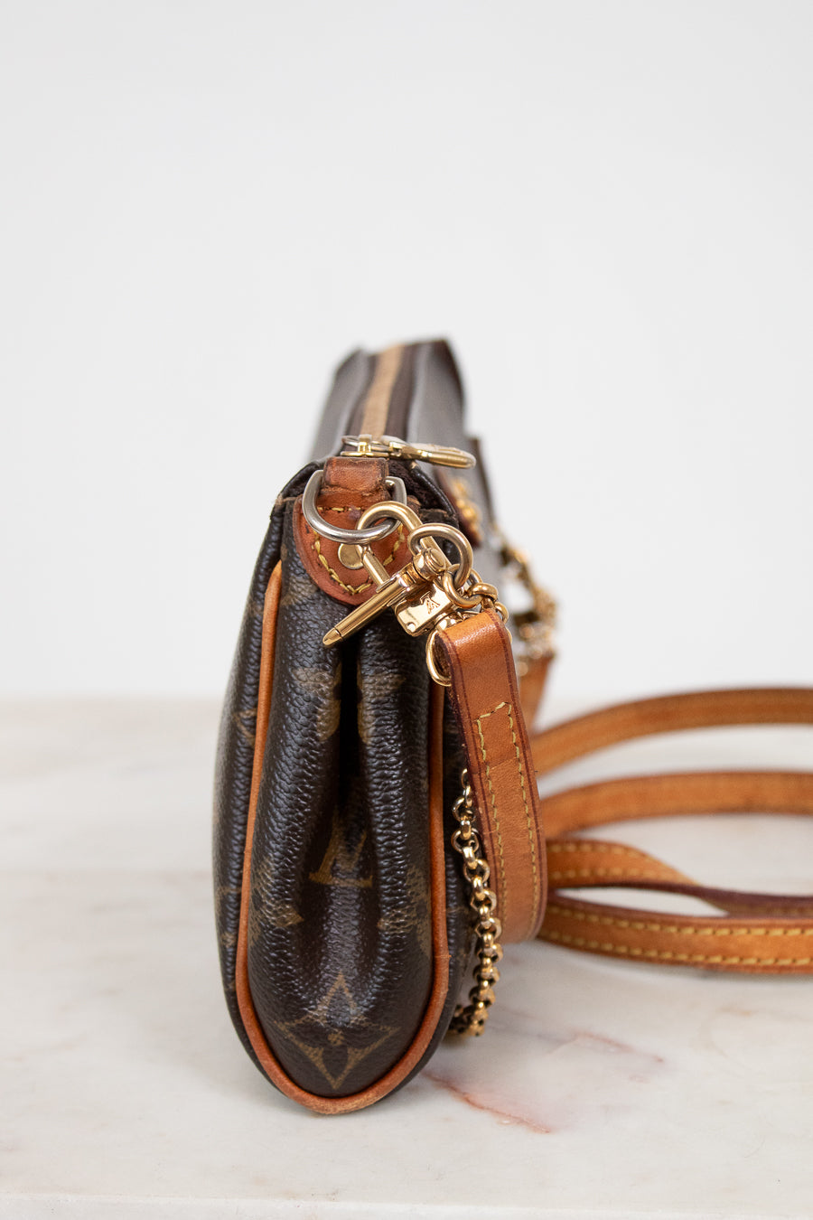 Brown leather handbag with gold accents on a light background