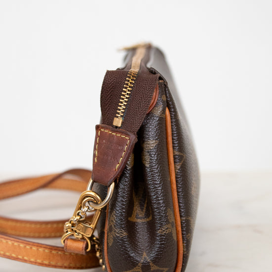 Brown leather handbag with gold accents on a light background