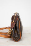 Brown leather handbag with gold accents on a light background